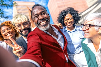 Különböző korú, fajú és nemű emberek mosolyognak az épületen kívül