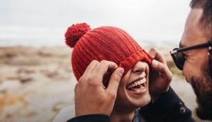 Egy nő mosolyogva, hátizsákban sétál barátjával, vidéken