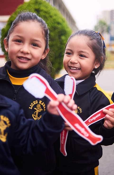 Smiling girls holding colgate toothbrushes Smiling girls holding colgate toothbrushes