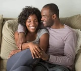 Kanapén ülő, nevetgélő és beszélgető pár.